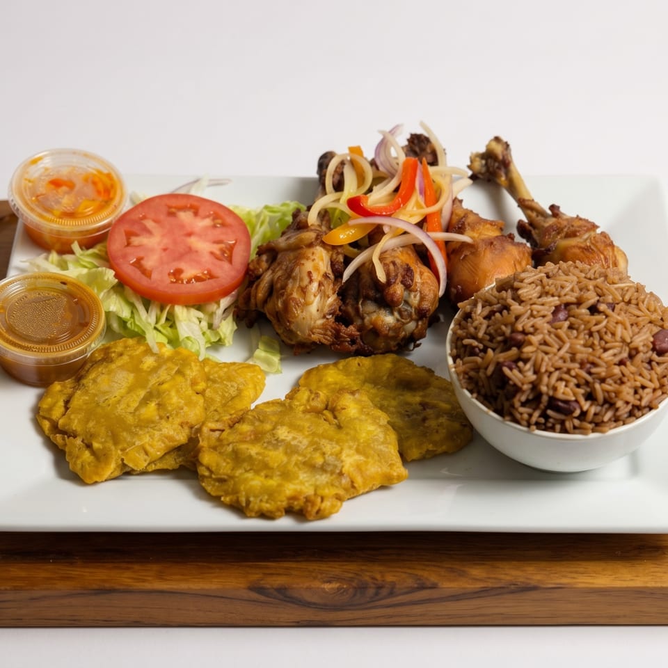 Fried chicken with rice and beans, plantains, and a side salad with dressing cups of two sauces.